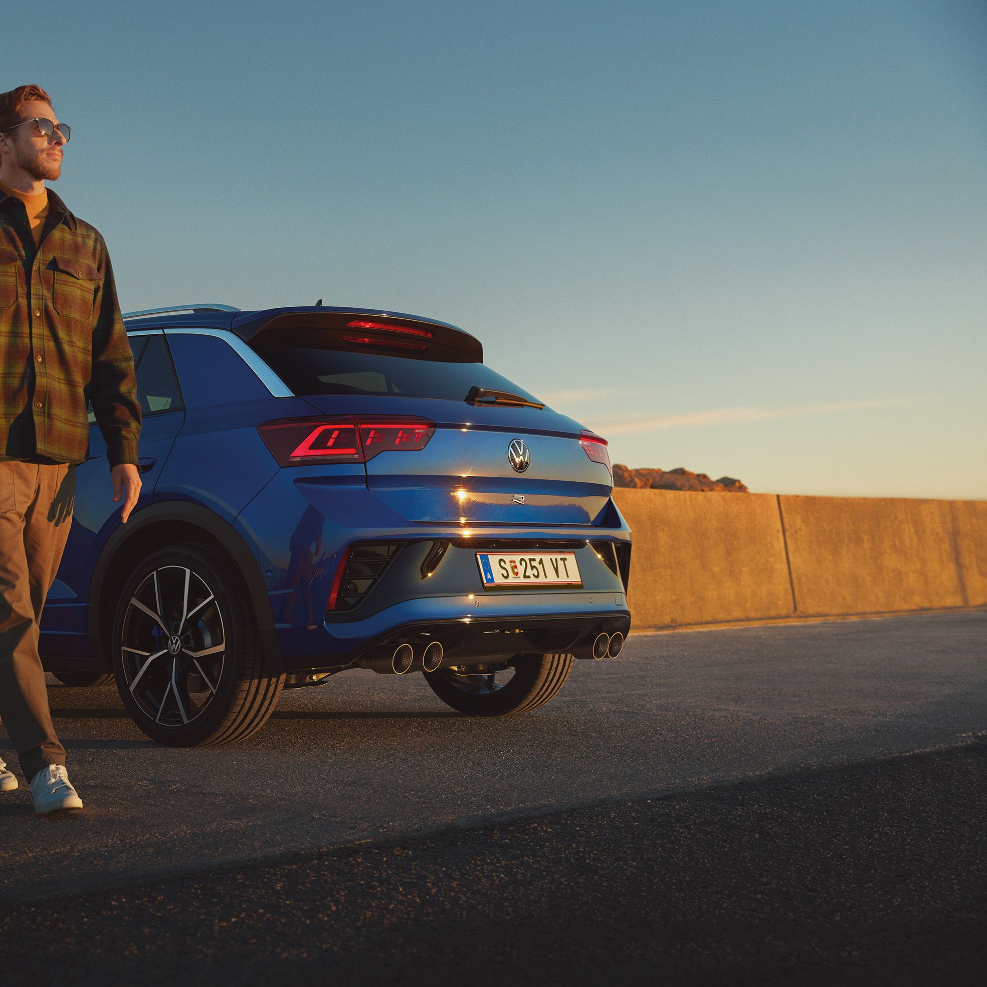 Mann geht an einem blauen VW T-Roc R vorbei