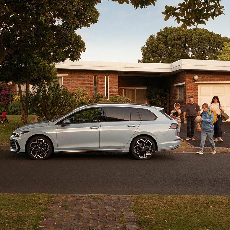 Seitenansicht eines VW Golf Variant in der Farbe Ice Blue Metallic geparkt vor Einfamilienhaus